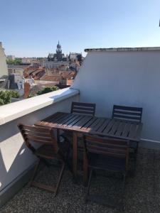 een houten tafel en 2 stoelen op een balkon bij Appartement avec vue panoramique in Vichy