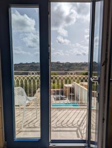 a sliding glass door leading to a patio with a chair at Sea Holly Gozo in Nadur