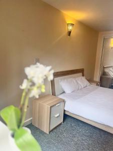 ein Hotelzimmer mit einem Bett und einem Tisch mit einer Blume in der Unterkunft Ensuite Private Room in Central Stylish Flat in Leicester