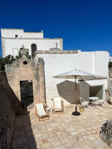 um pátio com cadeiras e um guarda-sol em frente a um edifício em Masseria Monè em Monopoli