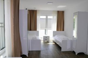 ein weißes Schlafzimmer mit 2 Betten und einem Spiegel in der Unterkunft Apartments & Pension Burglesum in Bremen