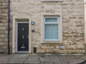 a brick building with a black door and two windows at 2 Brook Street in Clitheroe