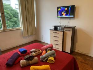 Habitación con cama con manta roja y TV. en Santana Temporada - Bolivar Apartments, en Río de Janeiro