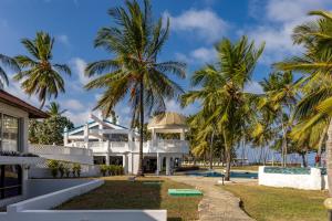 a white house with palm trees in front of it at Sun N Sand Beach Resort in Mombasa