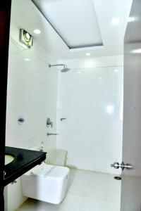 a white bathroom with a toilet and a sink at Hotel Suraj Palace in Bhopal