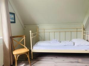 Una cama con sábanas blancas y una silla en una habitación en - Tulipa - Vakantiehuis nabij de bloembollenvelden, het meer en strand, en Noordwijkerhout