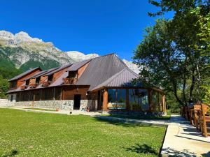 a large wooden building with mountains in the background at Royal Land in Theth