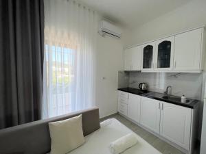 a kitchen with a couch and a sink and a window at Dine Apartments in Ksamil