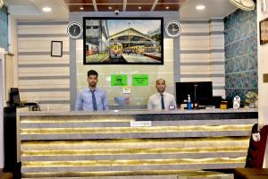 two men standing at a counter in a train station at Hotel Suraj Palace in Bhopal