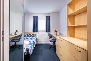 a room with a bed and a desk and chairs at Queen Margaret University Residences in Musselburgh