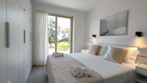 a white bedroom with a large bed with towels on it at Villa Vocetta vista mare in Serranova