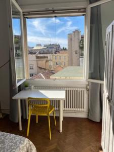 Marseille Vieux Port في مارسيليا: غرفة مع نافذة مع طاولة وكرسي اصفر