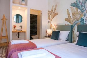 two beds in a room with a mirror and a sink at Succeed Campo Pequeno Suites in Lisbon