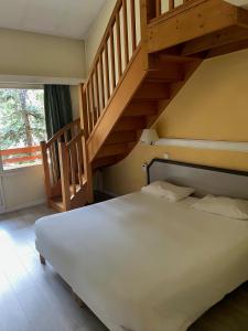 ブリッド・レ・バンにあるホテル アテナの白いベッドと木製の階段が備わるベッドルーム1室が備わります。