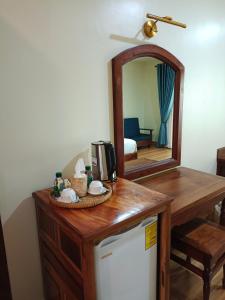 Habitación con mesa, espejo y nevera. en Sing Angkor Boutique Hotel, en Siem Reap