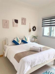 a bedroom with a large white bed with blue pillows at Sunset Paradise Moalboal in Moalboal