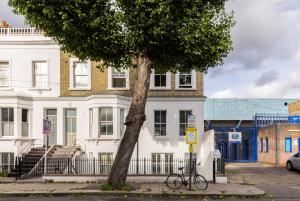 a bike parked next to a tree in front of a building at The Shepherd's Bush Luxury Villas in London