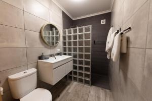 bagno con servizi igienici, lavandino e specchio di sweet home a Caniçal