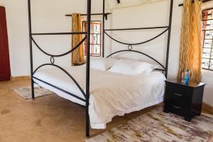Ndoto House-Maanzoni ,Athi River by Nest & Nomad في Machakos: غرفة نوم مع سرير بأربعة أعمدة أسود