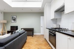 a living room with a couch and a kitchen at The Shepherd's Bush Luxury Villas in London