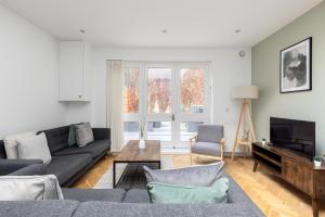 a living room with a couch and a tv at The Shepherd's Bush Luxury Villas in London