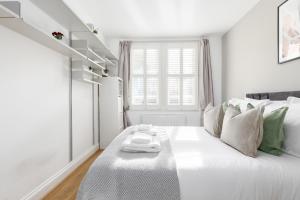 a white bedroom with a large white bed with a white scale on it at The Shepherd's Bush Luxury Villas in London