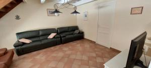 a living room with a black leather couch and a tv at Villa Mariella in Arles