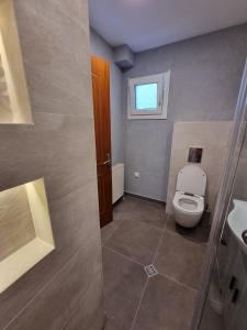 a bathroom with a toilet and a window at AApartment, Nea Peramos in Nea Peramos