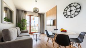 a living room with a couch and a table and a clock at City Center SPA Apartments Jaglana 6A with Parking in Gdańsk