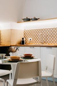 - une cuisine avec des placards blancs, une table et des chaises dans l'établissement Dal Monaco - casa vacanze, à Castellana Grotte