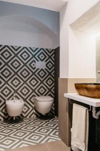 La salle de bains est pourvue de toilettes et de carrelage géométrique. dans l'établissement Dal Monaco - casa vacanze, à Castellana Grotte
