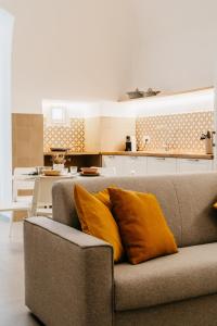 - un canapé avec deux oreillers orange dans le salon dans l'établissement Dal Monaco - casa vacanze, à Castellana Grotte