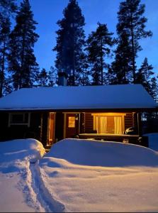una casa cubierta de nieve frente a una cabaña en Unique winter holiday in pine forest, en Forssa