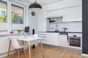 a kitchen with white cabinets and a table and chairs at Osiedle Życzeń Apartment Stawowa Cracow by Renters in Krakow