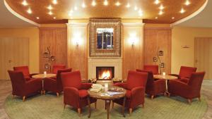 eine Lobby mit Tischen und Stühlen und einem Kamin in der Unterkunft Ostseehotel Villen im Park - ein Rovell Hotel in Bansin