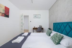 Schlafzimmer mit einem großen Bett mit blauem Kopfteil in der Unterkunft Osiedle Życzeń Apartment Stawowa Cracow by Renters in Krakau