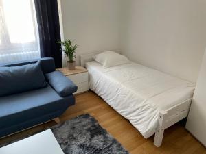 um pequeno quarto com uma cama e um sofá azul em Chambre privée proche centre et gare 2 em Besançon