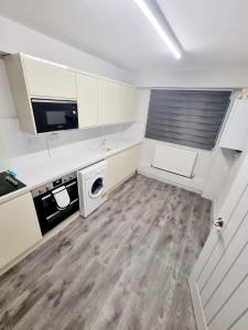 a kitchen with white cabinets and a wooden floor at Luxurious home in Pitsea