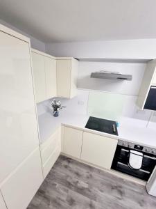 uma cozinha branca com armários brancos e um fogão em Luxurious home em Pitsea