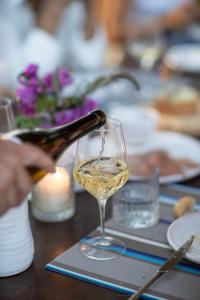グラダーラにあるCastello di Granarola - Dimora storica, Suites e Appartamentiの白ワインをグラスに注ぐ者