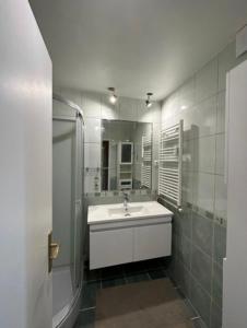 La salle de bains blanche est pourvue d'un lavabo et d'une douche. dans l'établissement Chambre dans appartement chez habitants À côté du Lac et du Casino, à Épinay-sur-Seine