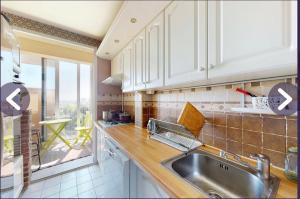a kitchen with white cabinets and a sink and a window at Chambre dans appartement chez habitants À côté du Lac et du Casino in Épinay-sur-Seine