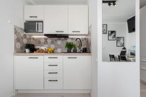a white kitchen with white cabinets and appliances at Czarnowiejska Mini Studio in Kraków