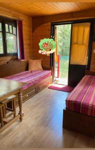 a room with two beds and a table and a window at La roulotte de La Motte in La Motte