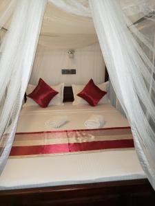 a white bed with red pillows in a tent at Hotel Alaskabay Arugambay in Pottuvil