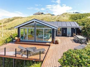 una casa en una terraza de madera con puertas de cristal en 6 person holiday home in L kken, en Løkken