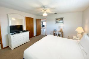 a bedroom with a white bed and a flat screen tv at Island Charm in St. George Island