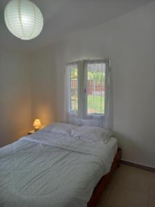 - une chambre blanche avec un lit et une fenêtre dans l'établissement La grenadine, à Sainte-Anne-les Hauts