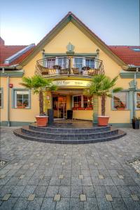 un edificio amarillo con palmeras delante en Wellness Hotel Kager Harkány, en Harkány