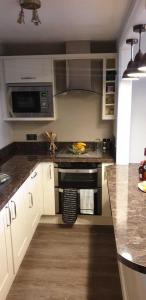 Una cocina con gabinetes blancos y una estufa negra. en Seaview Apartment Sleeps 2 -Patio -WiFi -Tv, en Barmouth 10 fotos más